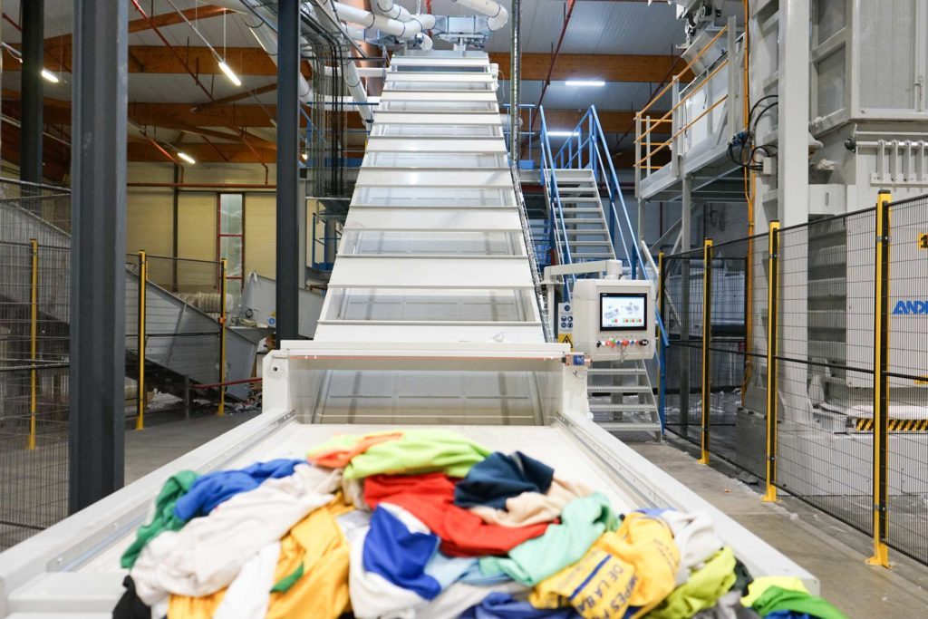 Chaîne industrielle automatisée de recyclage avec une pile de vêtements dessus