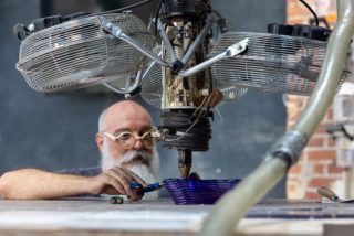 Homme en train de travailler du verre via une machine avec des ventilateurs