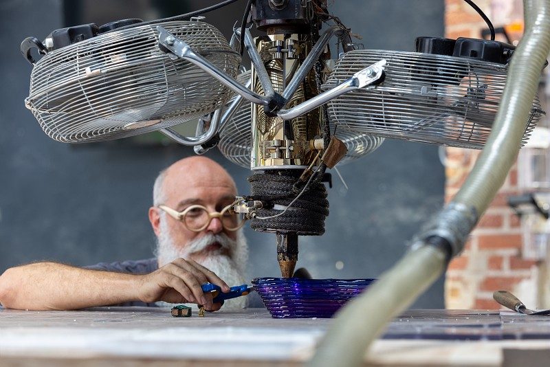 Homme en train de travailler du verre via une machine avec des ventilateurs