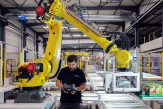 Homme qui télé-commande un grand bras industriel jaune