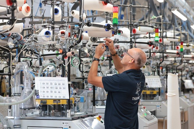 Homme en train de travailler des fil de tissu sur une machine industrielle