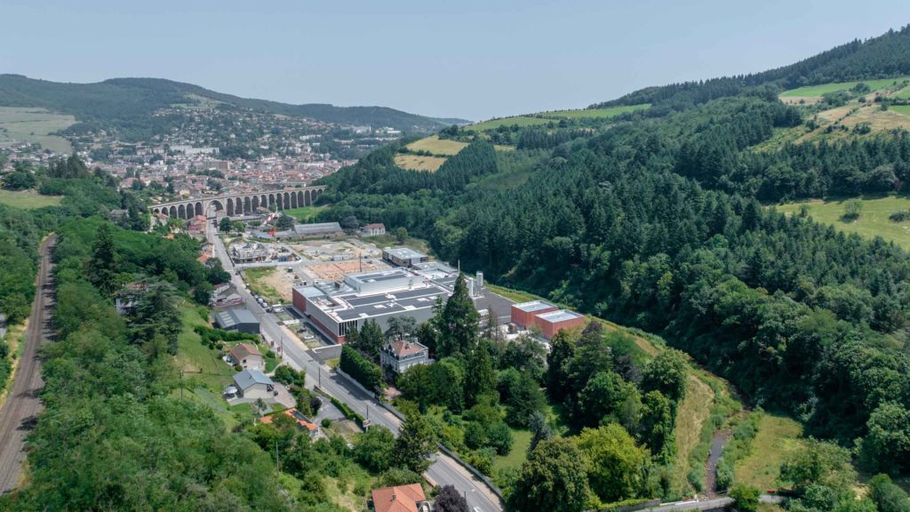 Vue aérienne d'un bâtiment de production avec un viaduc en fond