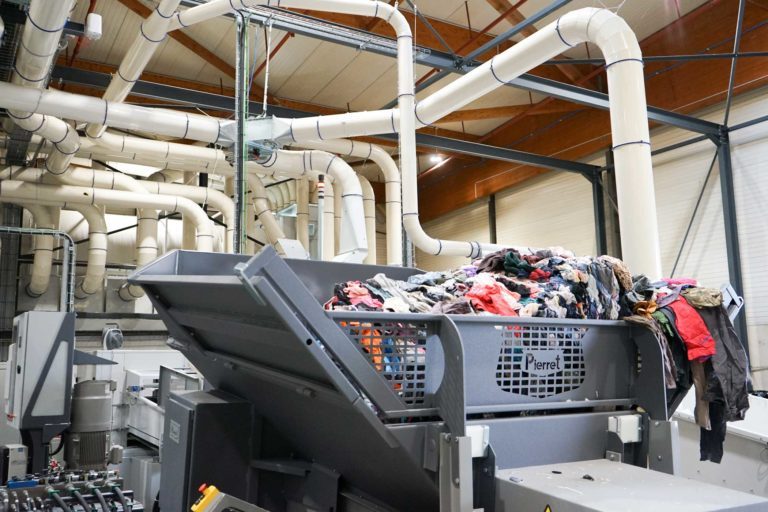 Benne dans une usine de recyclage avec des vêtements dedans