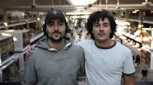 Deux homme bras dessus bras dessous devant une galerie marchande