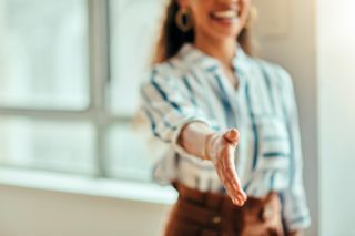 Femme qui tend la main vers l'objectif pour une poignée de main