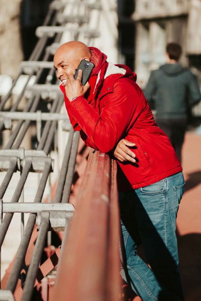 Homme au téléphone accoudé à la barrière d'un pont