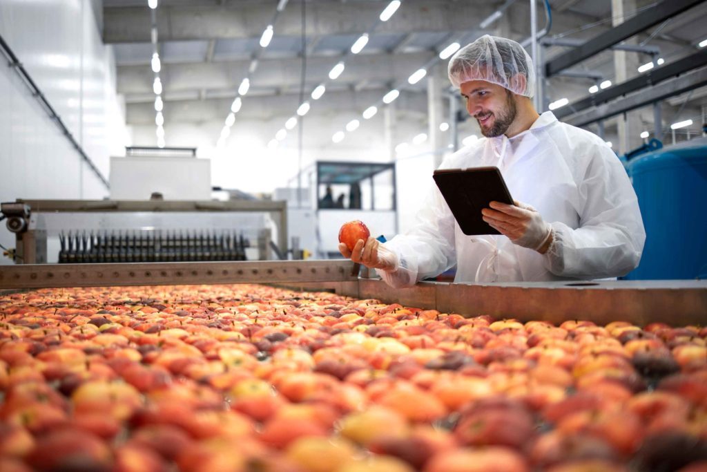 Homme en blouse devant une rangée de pommes
