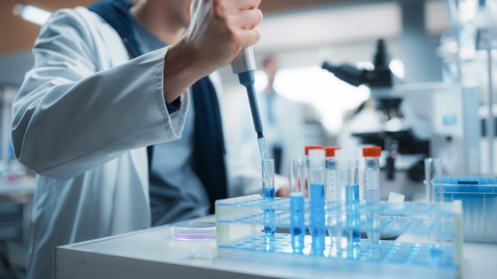 scientifique qui utilise une micropipette dans des fioles