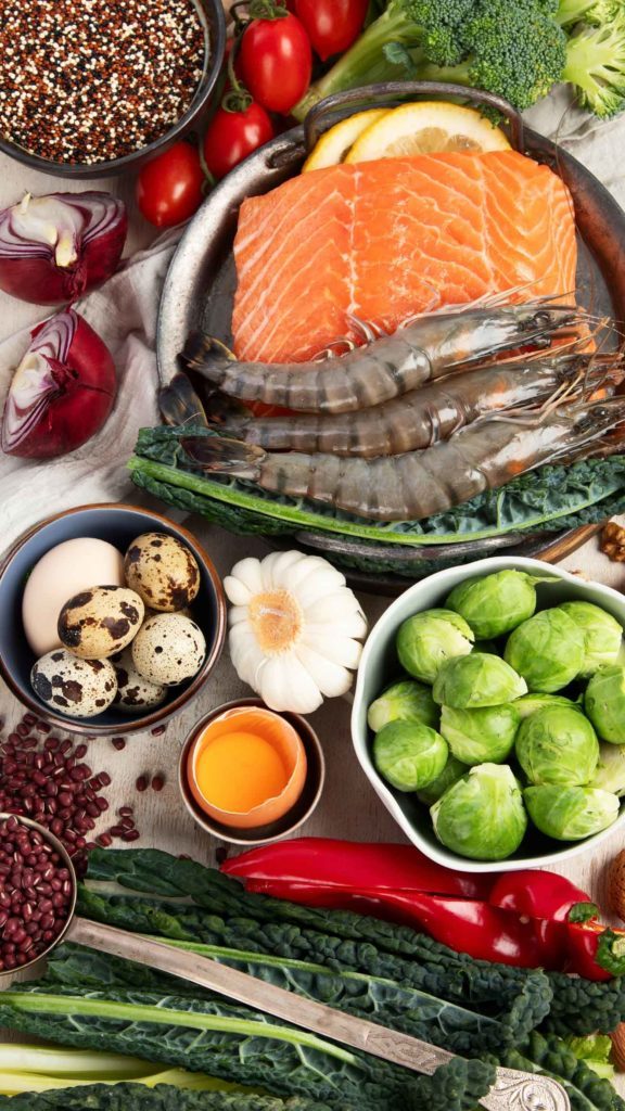 Plusieurs plats sur une table ; du saumon, des gambas, des choux de bruxelles et des oeufs