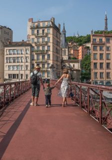 Un couple qui tient les mains de leur enfant sur la passerelle Saint-Vincent à Lyon