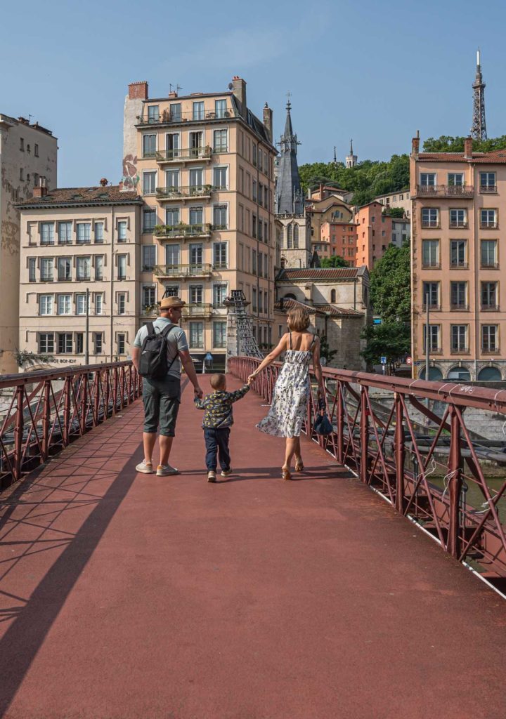 Un couple qui tient les mains de leur enfant sur la passerelle Saint-Vincent à Lyon
